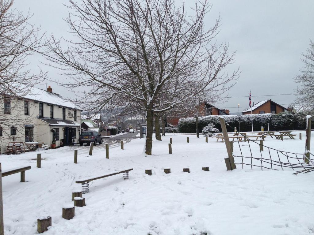 un patio cubierto de nieve con bancos y un árbol en The Swan at Great Kimble en Aylesbury