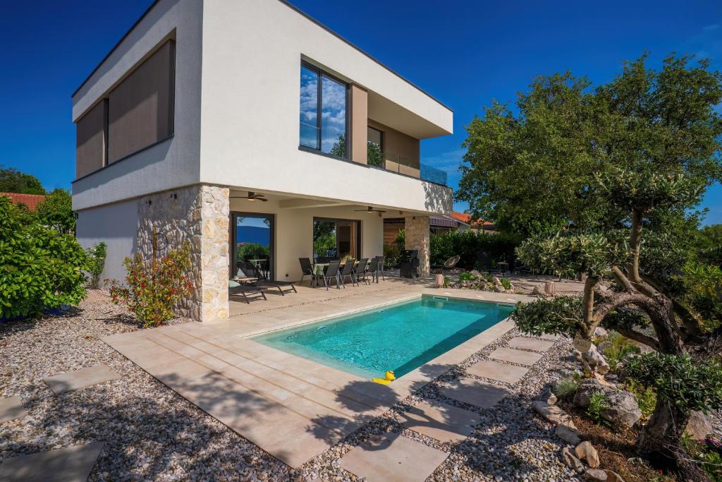 a house with a swimming pool in front of it at Villa Elementa Krk - Luxury Four Elements Experience in Krk