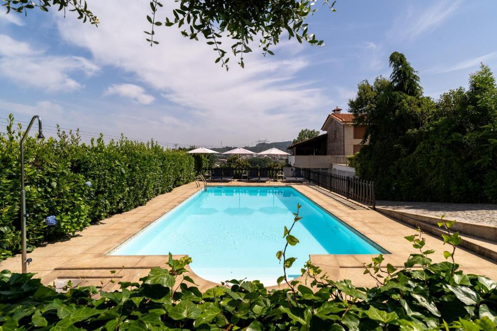 a swimming pool in the middle of a garden at Casas da Aldeia da Graça in Guimarães