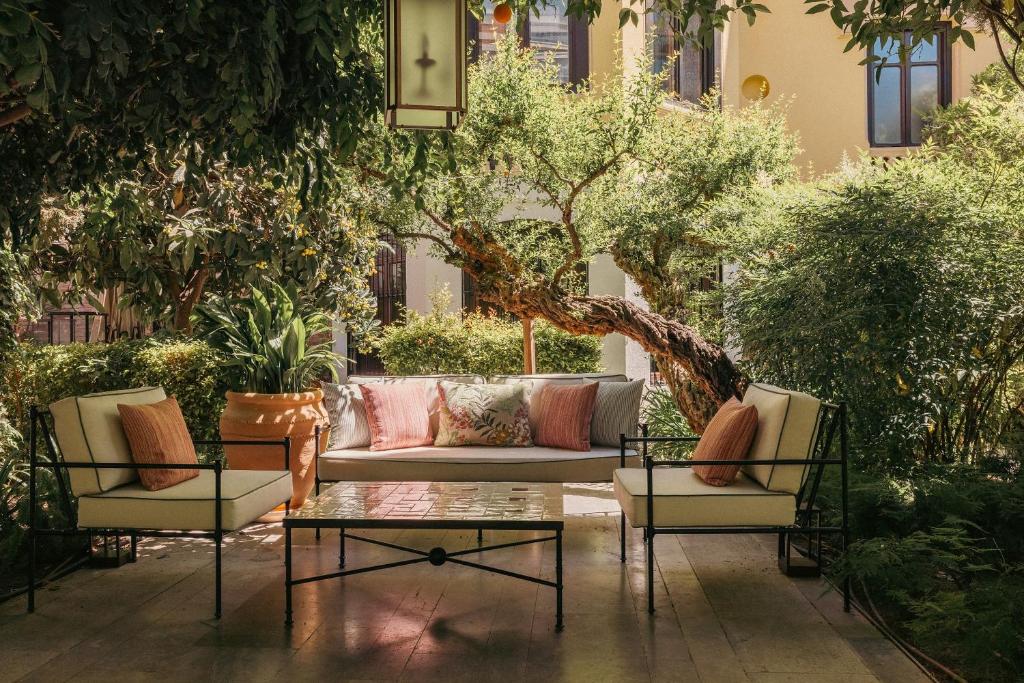 a patio with couches and a table and trees at Hospes Palacio de los Patos, a Member of Design Hotels in Granada