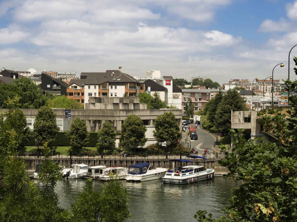a group of boats are docked in a river at ibis Nogent Sur Marne RÉNOVÉ EN 2025 in Nogent-sur-Marne