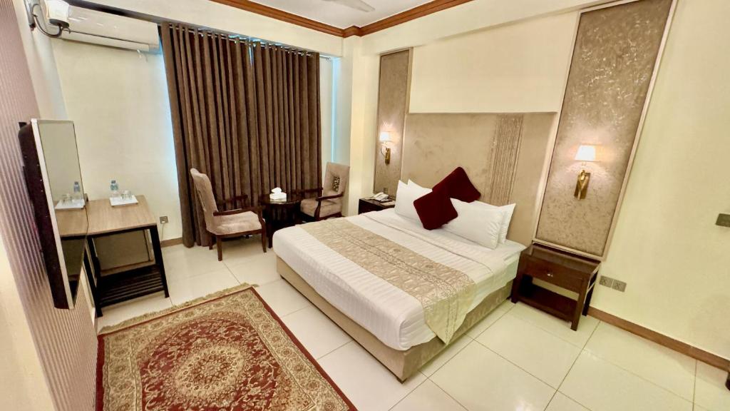 a hotel room with a bed and a chair and a window at Shelton's Rezidor Peshawar in Peshawar