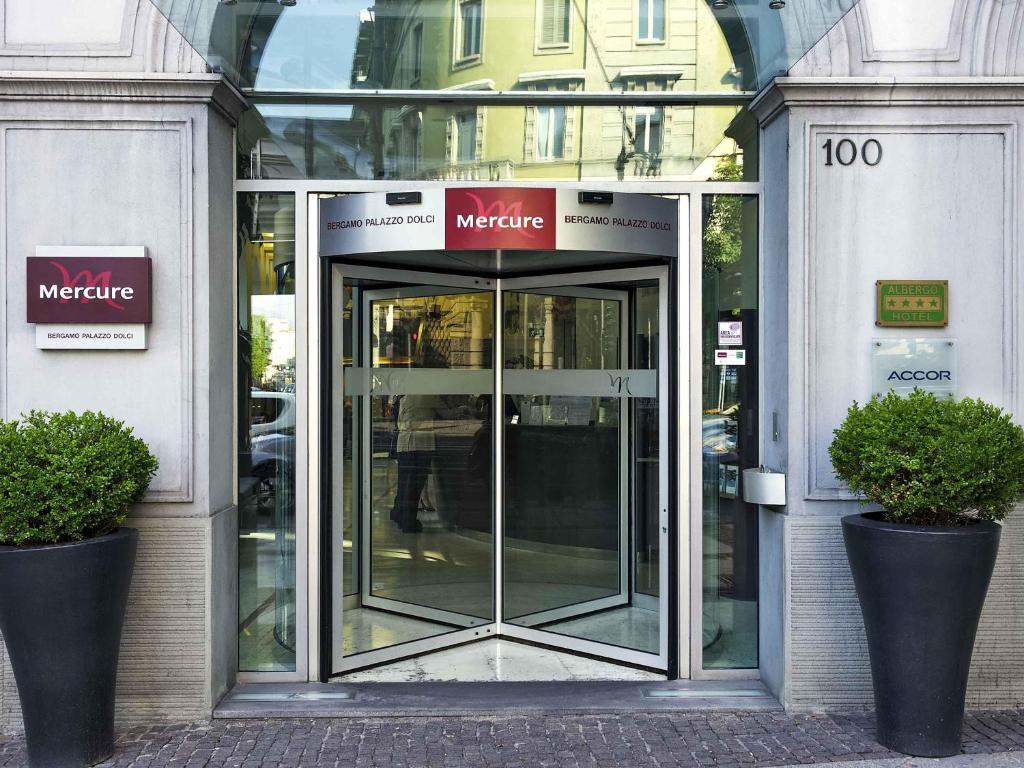 a revolving door in a building with two plants at Mercure Bergamo Centro Palazzo Dolci in Bergamo