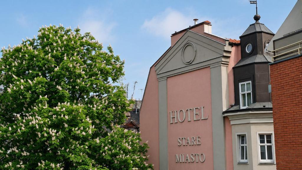 a building with the words hotel on it next to a tree at Hotel Stare Miasto Old Town in Poznań
