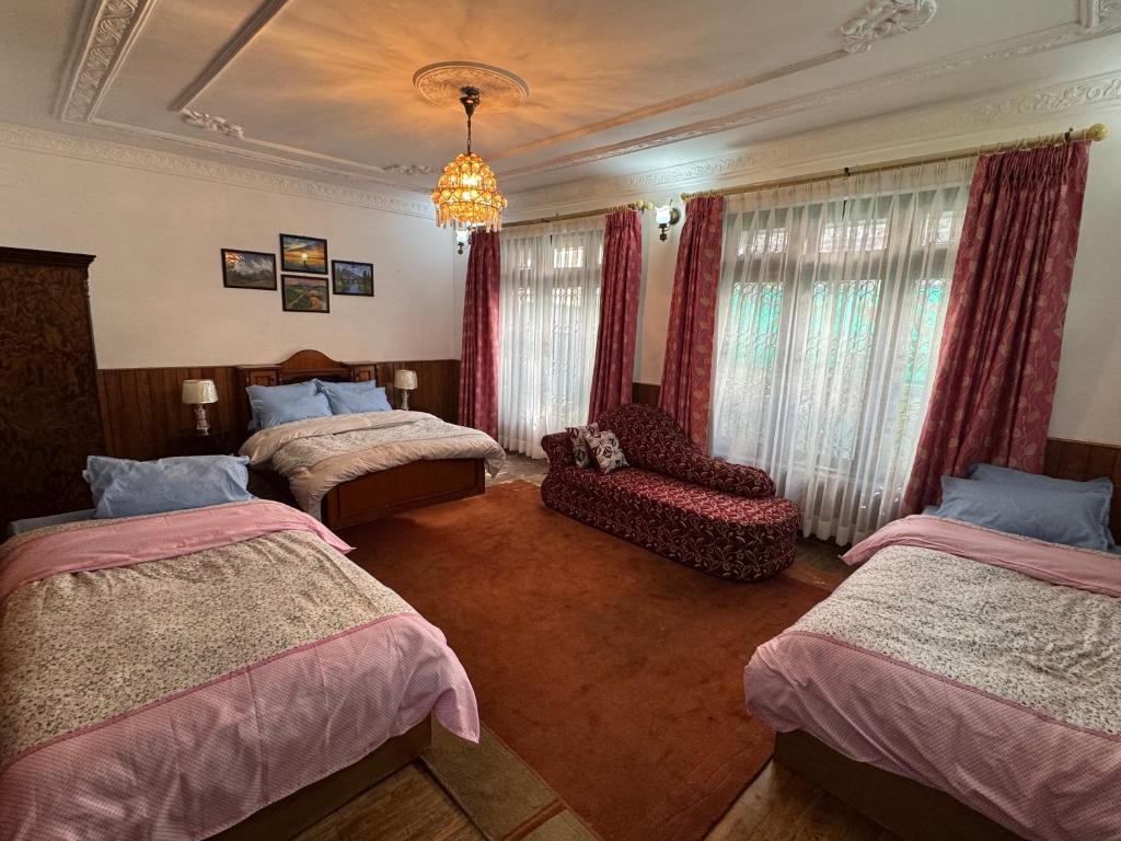 a bedroom with two beds and a chair and a chandelier at Pahuna Homestay in Kathmandu