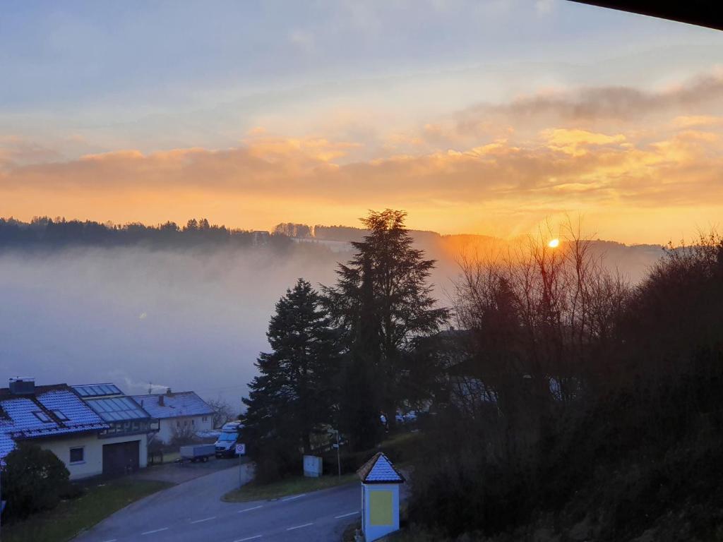 a misty sunrise with the sun rising over a town at Auszeit am Fluss - Donau in Obernzell