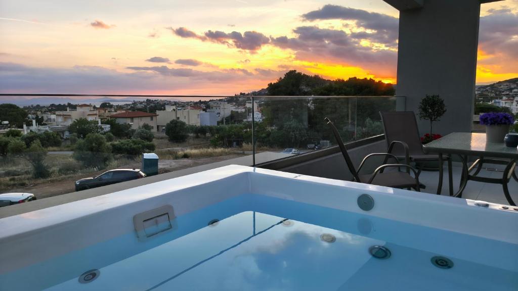 a hot tub on the balcony of a house with a sunset at Sunset Horizon Lagonisi in Kalívia Thorikoú