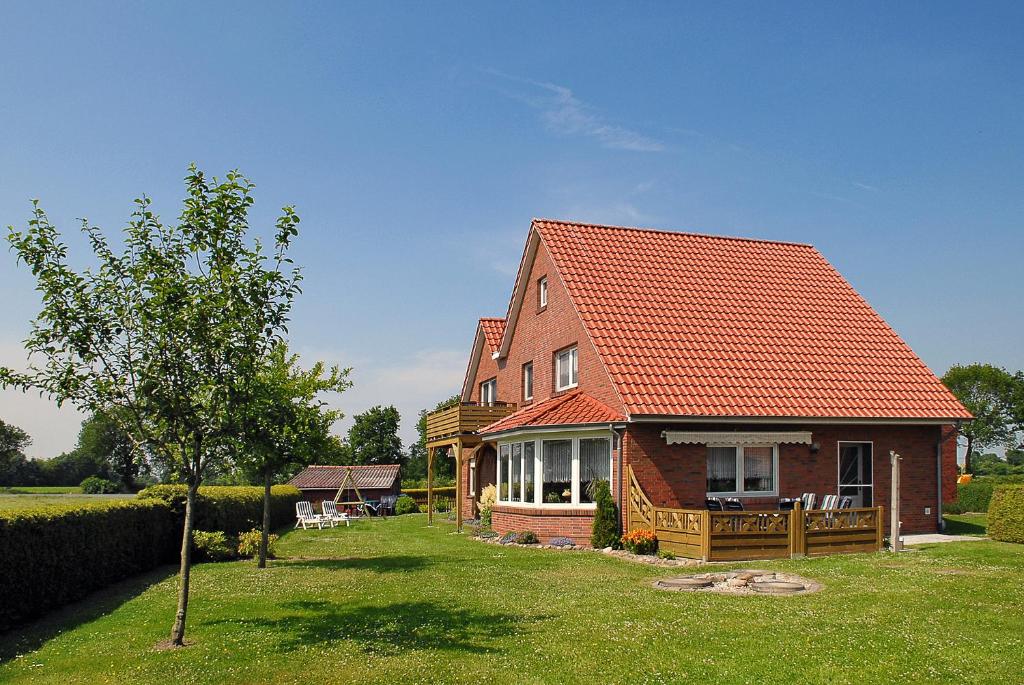 a house with an orange roof on a green yard at Ferienwohnung im Haus Katja in Dunum