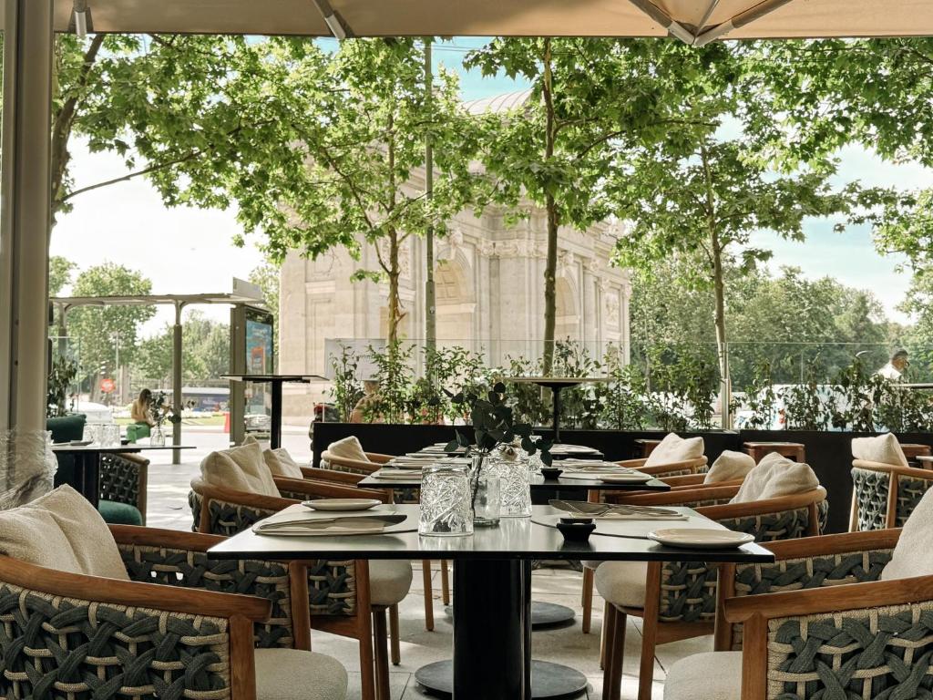 a restaurant with tables and chairs and trees at Hospes Puerta de Alcalá, a Member of Design Hotels in Madrid