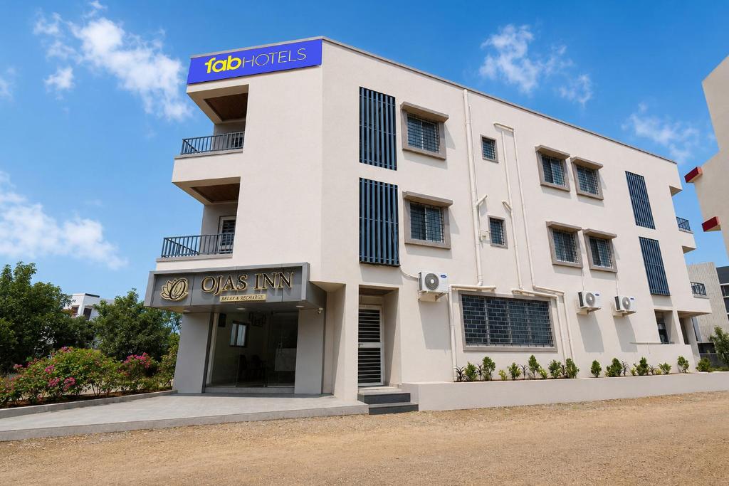 a white building with a blue sign on it at FabHotel Ojas Inn in Pune