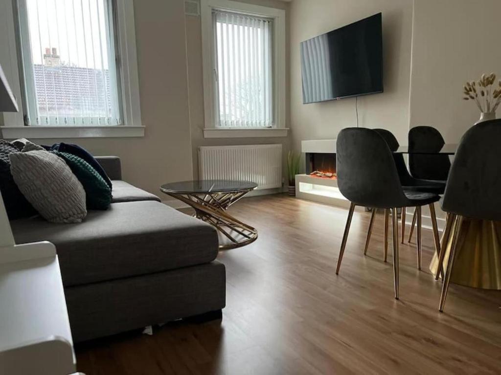 a living room with a couch and a table and a television at 3 Bedroom Flat - Sleeps 6 - Free Parking in Kirkcaldy