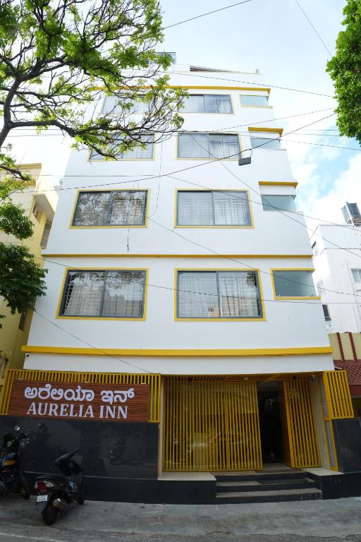 a tall white building with a sign in front of it at Aurelia INN - JP Nagar in Bangalore