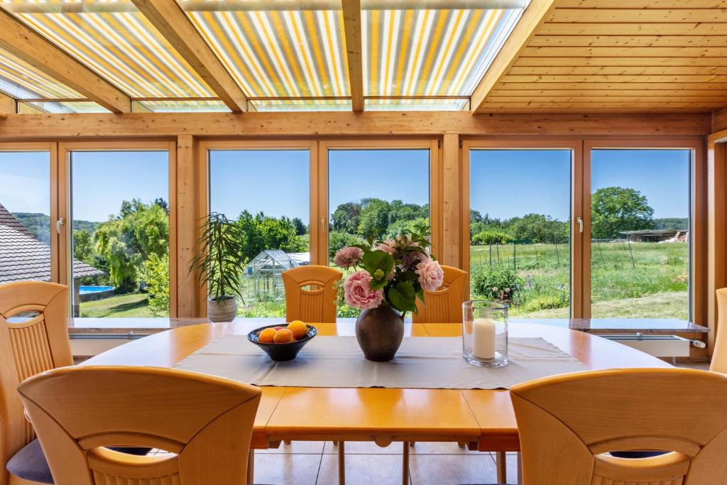 a dining room with a table with a vase of flowers at Landzeit in Efringen-Kirchen