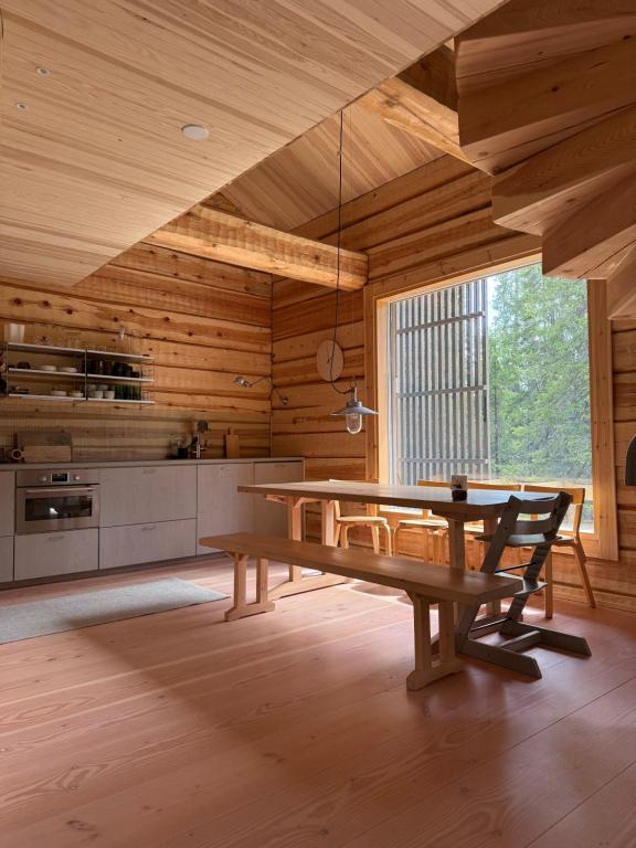 a dining room with a table and a large window at Handcrafted Log Chalet Villa Aarreaitta in Syöte