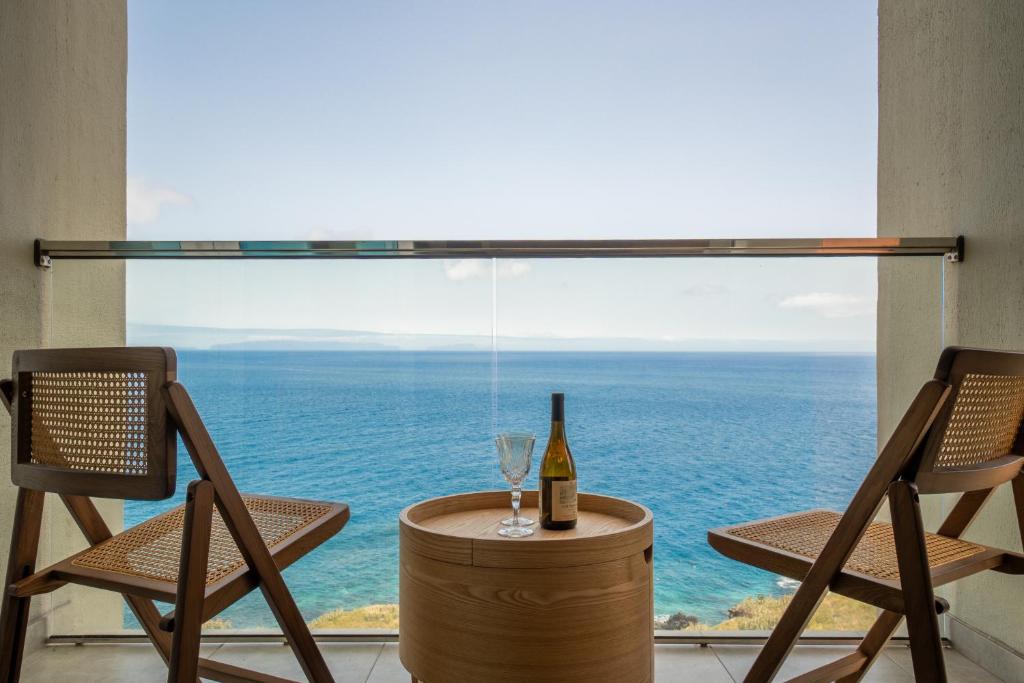 a bottle of wine sitting on a table with two chairs at Horizon living Madeira in Caniço