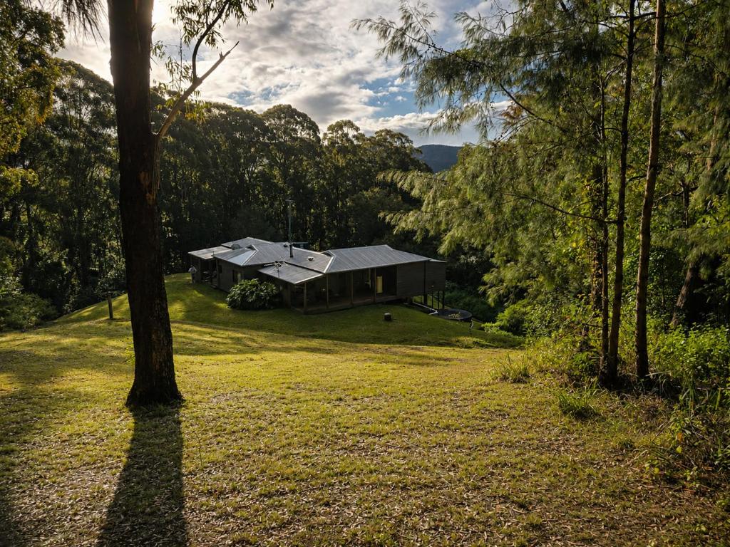 a house in the middle of a field with trees at Thrums Bush Retreat in Upper Orara