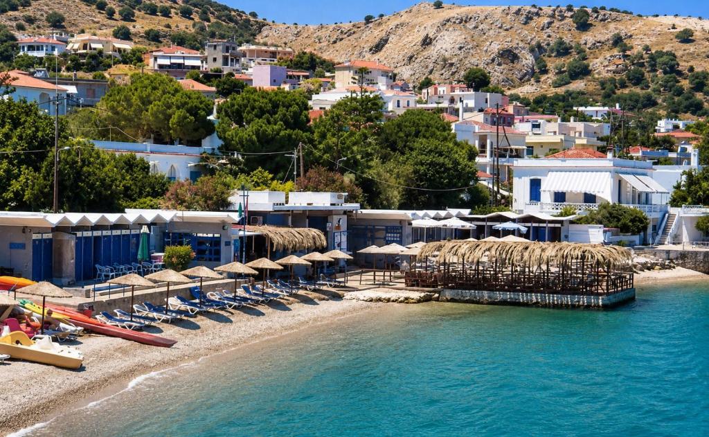 a beach with umbrellas and chairs and the water at Elegant Studio in Chios near the Beach and Port in Chios