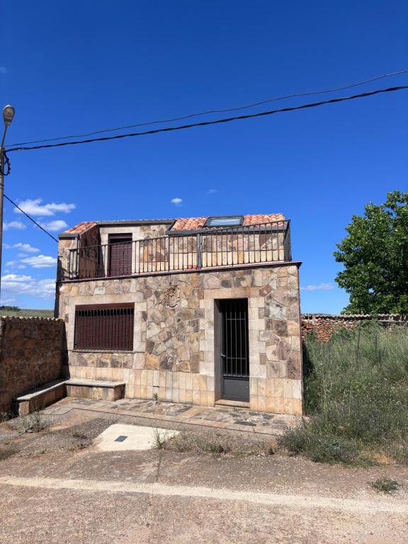 a stone building with a gate and a blue sky at Casa Familiar Mazalvete in Mazalvete