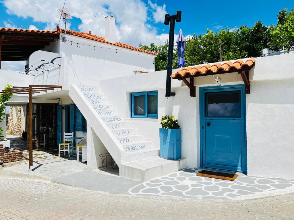 a white house with a blue door and stairs at Aloni Petit House in Nerotriviá