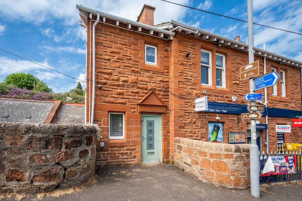 a brick building with a green door on a street at Culzean Road, Retreat in Maybole