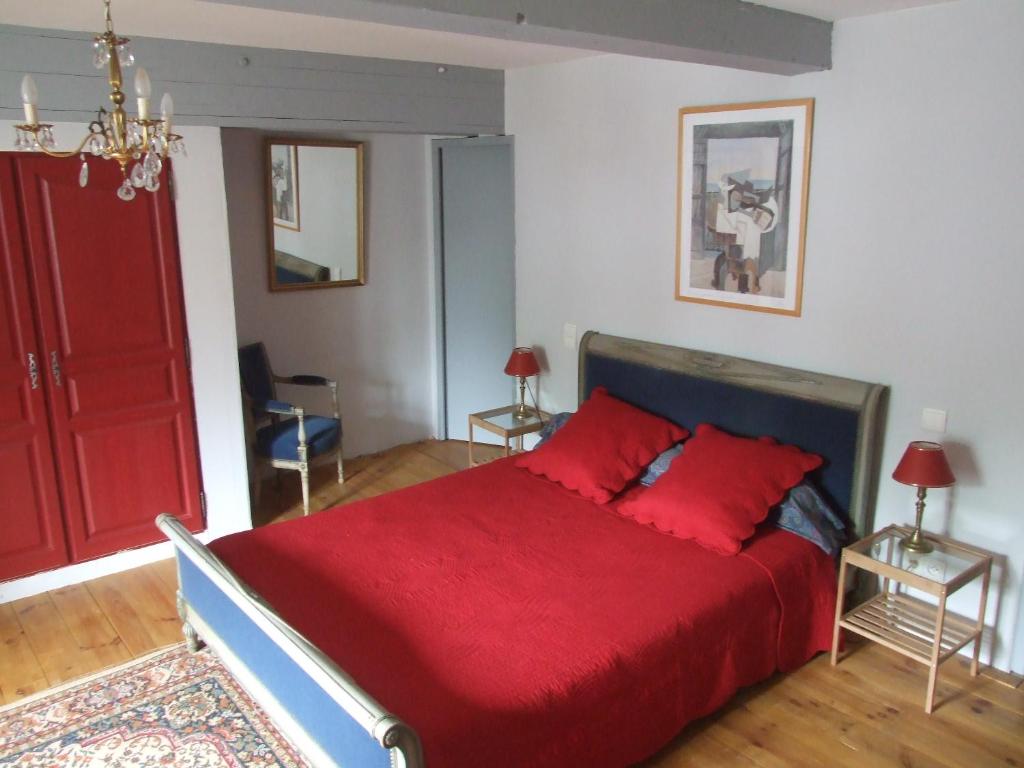 1 dormitorio con cama roja y puerta roja en Chambres d'hôtes Ferme de Gayri, en Vielle-Aure