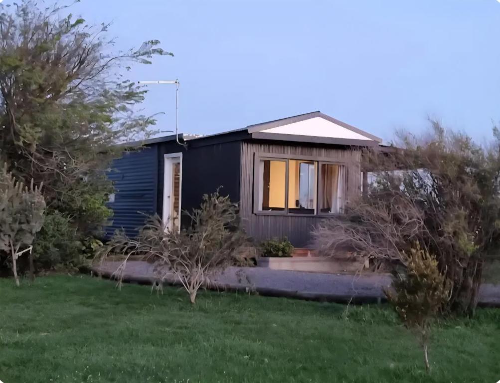 a small black house with a yard at Farmstay in Elingamite North
