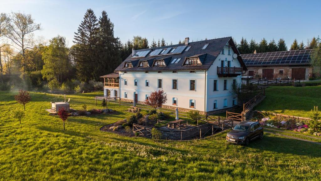 a large white house with a car parked in front of it at Penzion Stanský Mlýn in Hlinsko