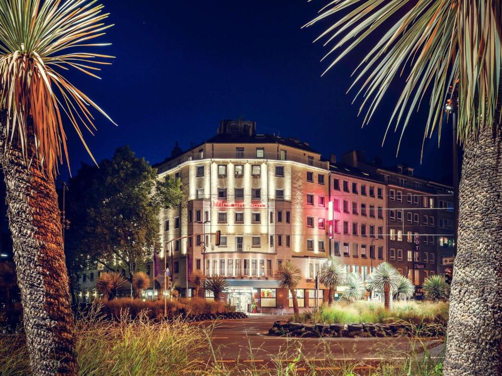 ein großes weißes Gebäude, das nachts beleuchtet ist in der Unterkunft Mercure Hotel Düsseldorf City Center in Düsseldorf