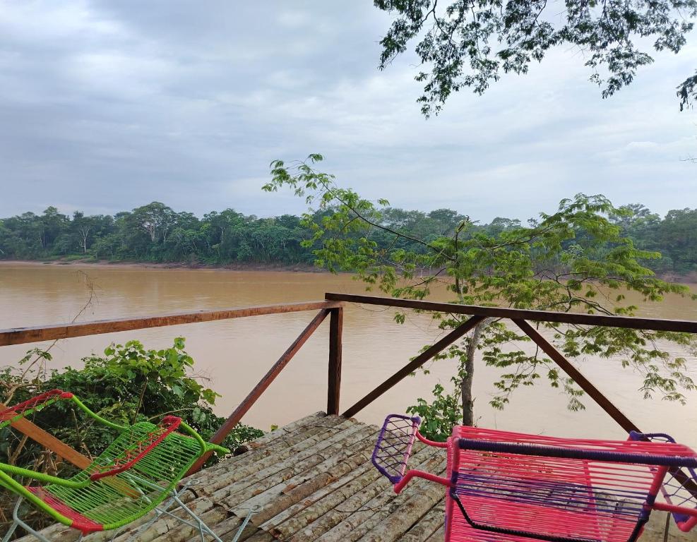 two chairs sitting on a dock next to a river at Musas Garden Lodge Tambopata in Puerto Maldonado