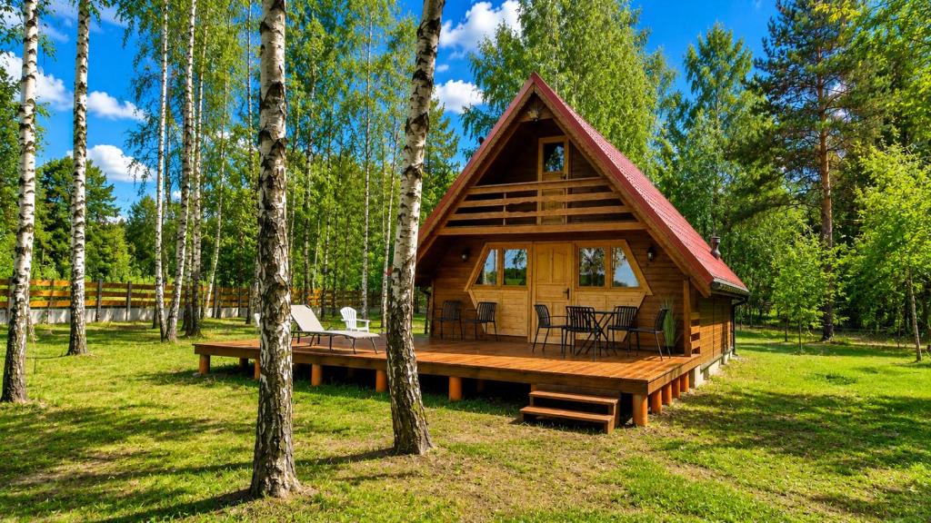 a log cabin with a deck in the woods at Wypoczynek "POD BRZÓSTKAMI" in Nagłowice
