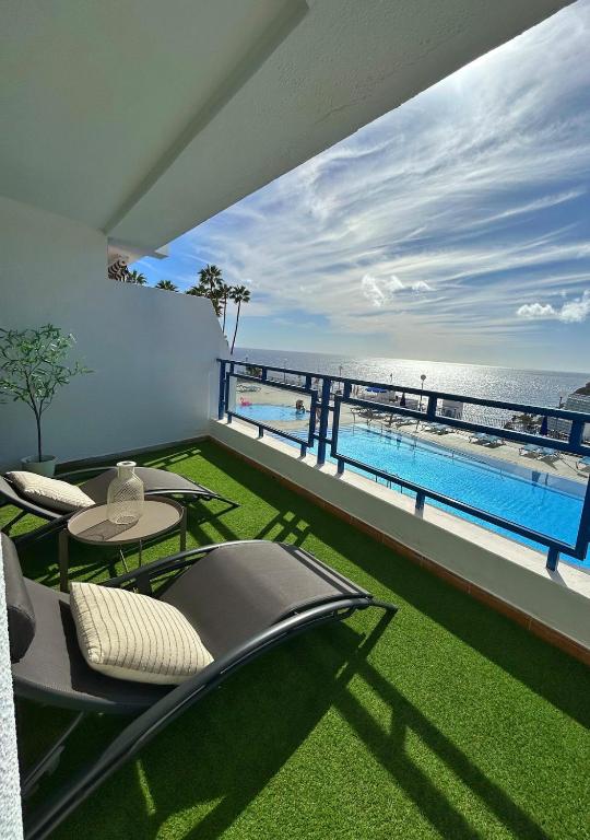 a balcony with a table and chairs and the ocean at Fish & Banana Beach House in Taurito