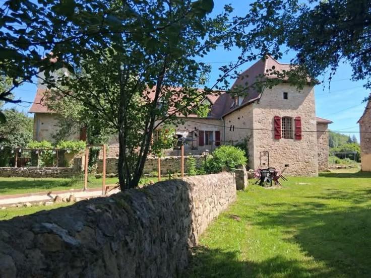 a stone wall in front of a large house at B&B maison du Saint Cirque in Saint-Dau