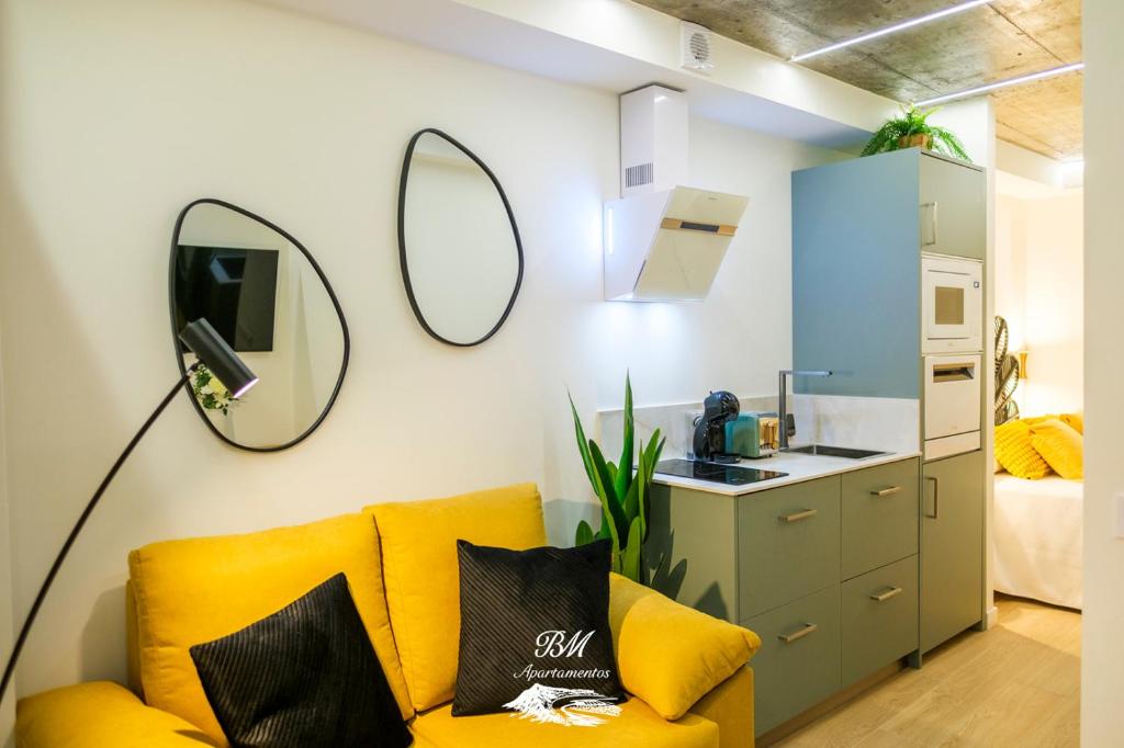 a living room with a yellow couch and a mirror at BM Apartamentos in Ribadesella