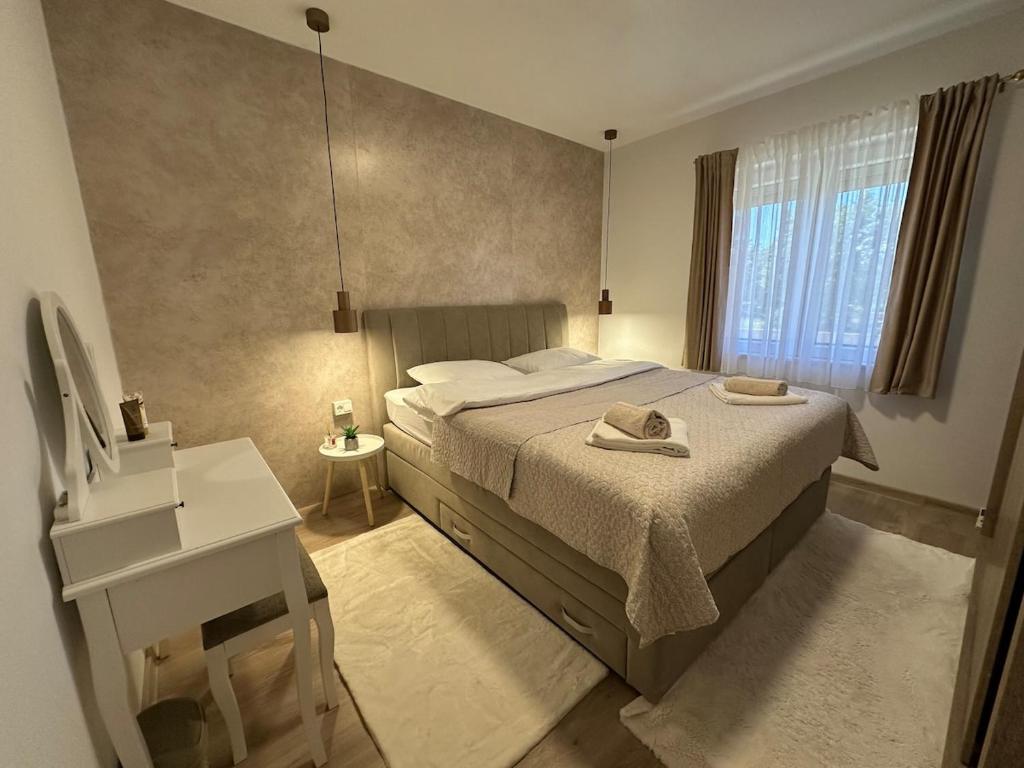 a bedroom with a bed and a desk and a window at Novi apartman Posušje in Posušje