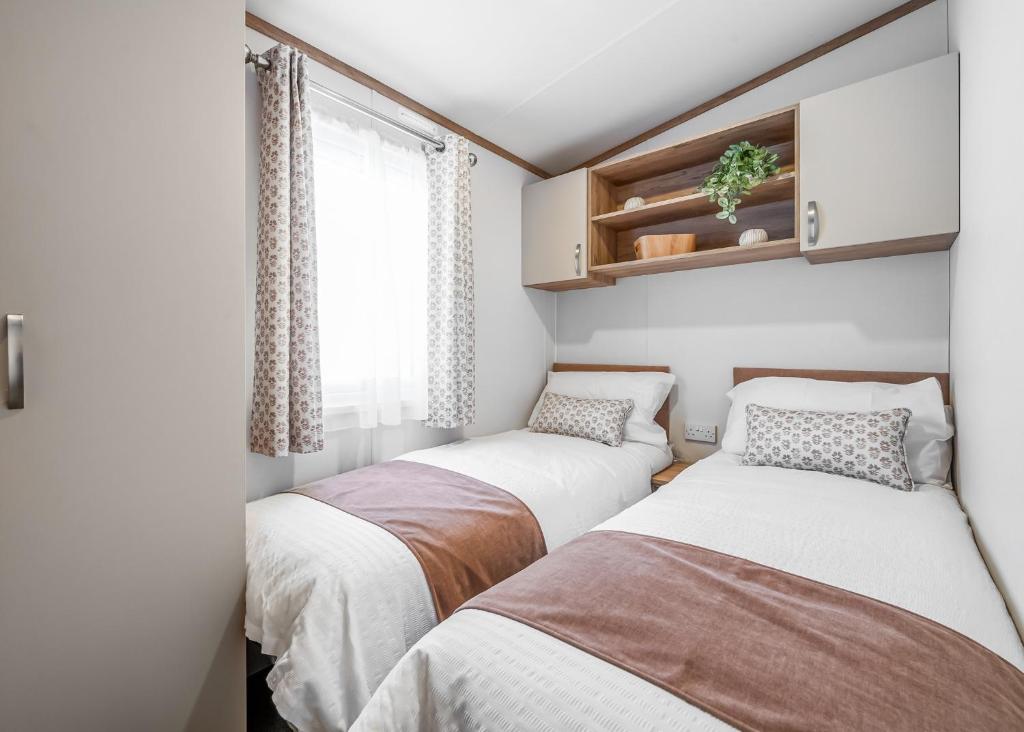 two beds in a small room with a window at Bosworth Lakeside Lodges in Carlton