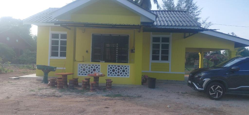 a small yellow house with stools in front of it at Rumah Kuning Homestay in Bachok