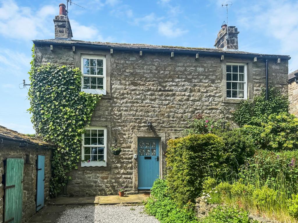 a stone house with a blue door and ivy at Emily's Cottage in Hebden