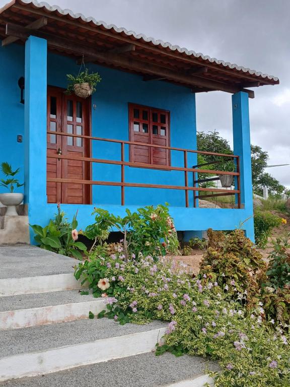 a blue house with flowers in front of it at Chalés Flor de Mandacaru in Monte das Gameleiras
