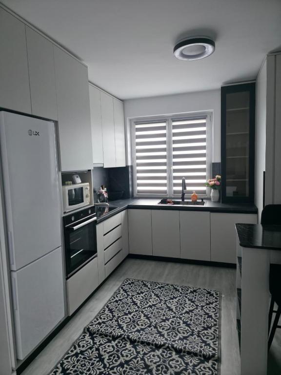 a kitchen with white cabinets and a black and white rug at The Cozy Velvet in Ocna-Mureşului