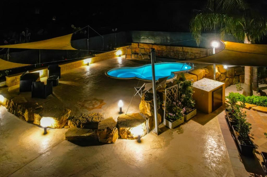an outdoor swimming pool at night with lights at Casale Sammartano - Appartamenti con piscina comune in Ummari