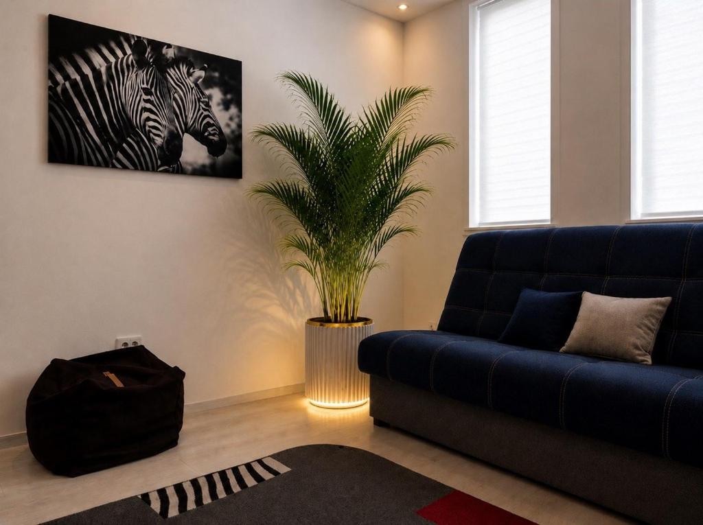 a living room with a blue couch and a plant at Апартаменти 2-кім Тарнавського in Ternopil