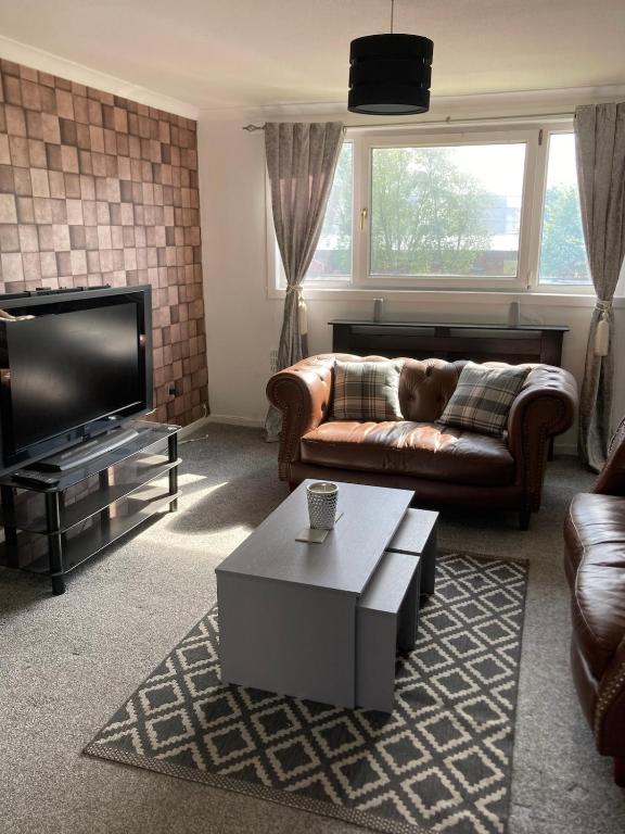 a living room with a couch and a flat screen tv at Great for commuting, budget friendly apartment in Dalmuir