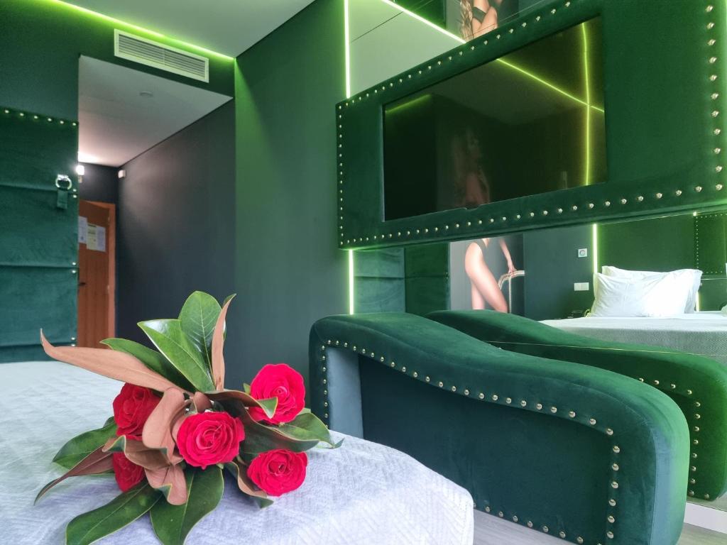 ein grünes Schlafzimmer mit einem Bett und einem Strauß roter Rosen in der Unterkunft Motel Século in Lousada