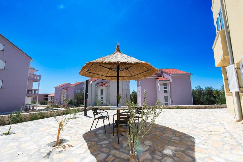 a table and chairs under an umbrella in a courtyard at Apartments Silvia in Novalja
