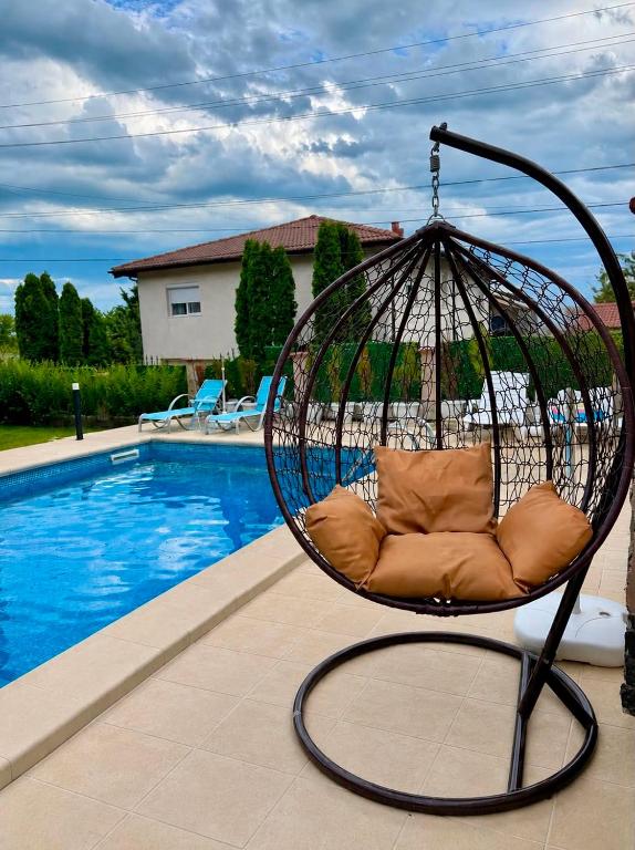 a swing chair sitting next to a swimming pool at Helena Guest House - Pool & Sea View in Balchik