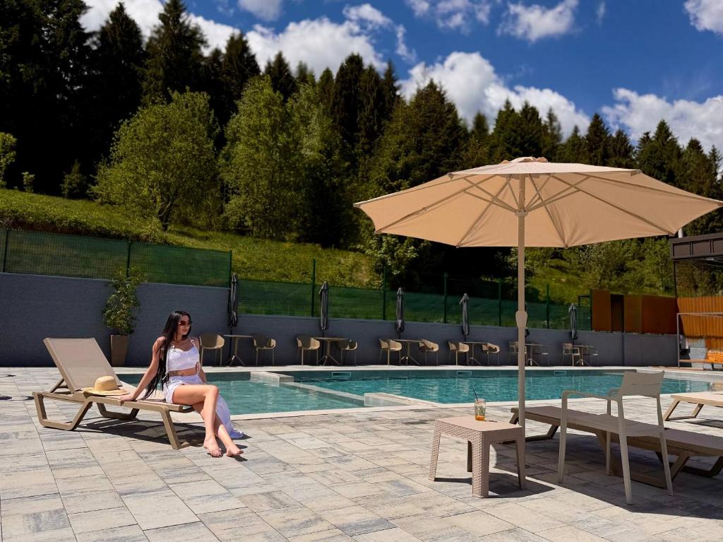 a woman sitting on a chair next to a swimming pool at Poeziya Mandriv in Skhidnitsa