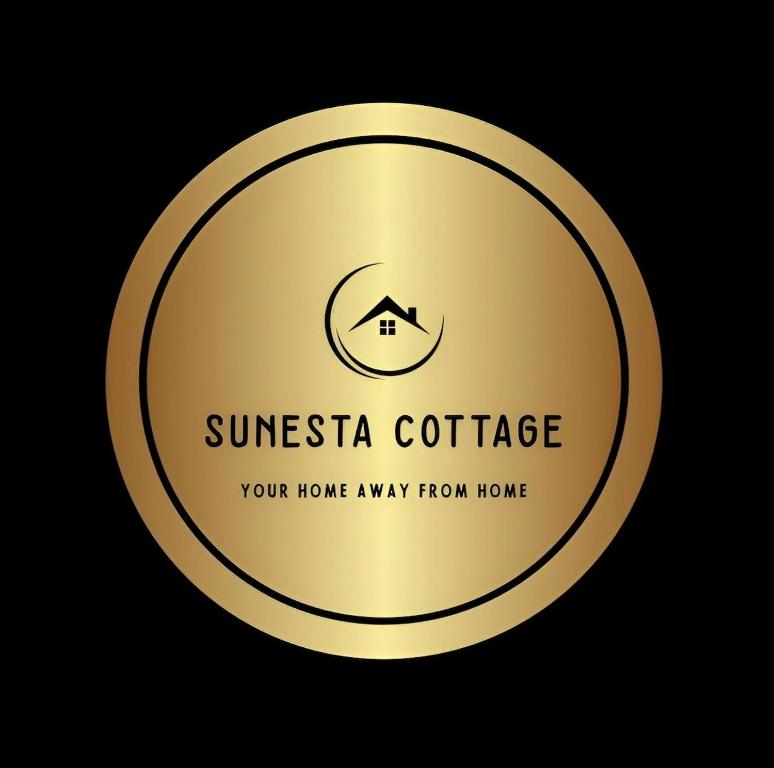 a gold circle with a logo of a house at Sunesta Cottage in Gqeberha