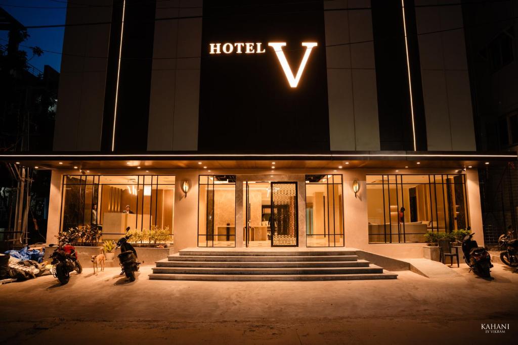 a hotel with motorcycles parked outside of it at night at Hotel V Kondapur in Hyderabad