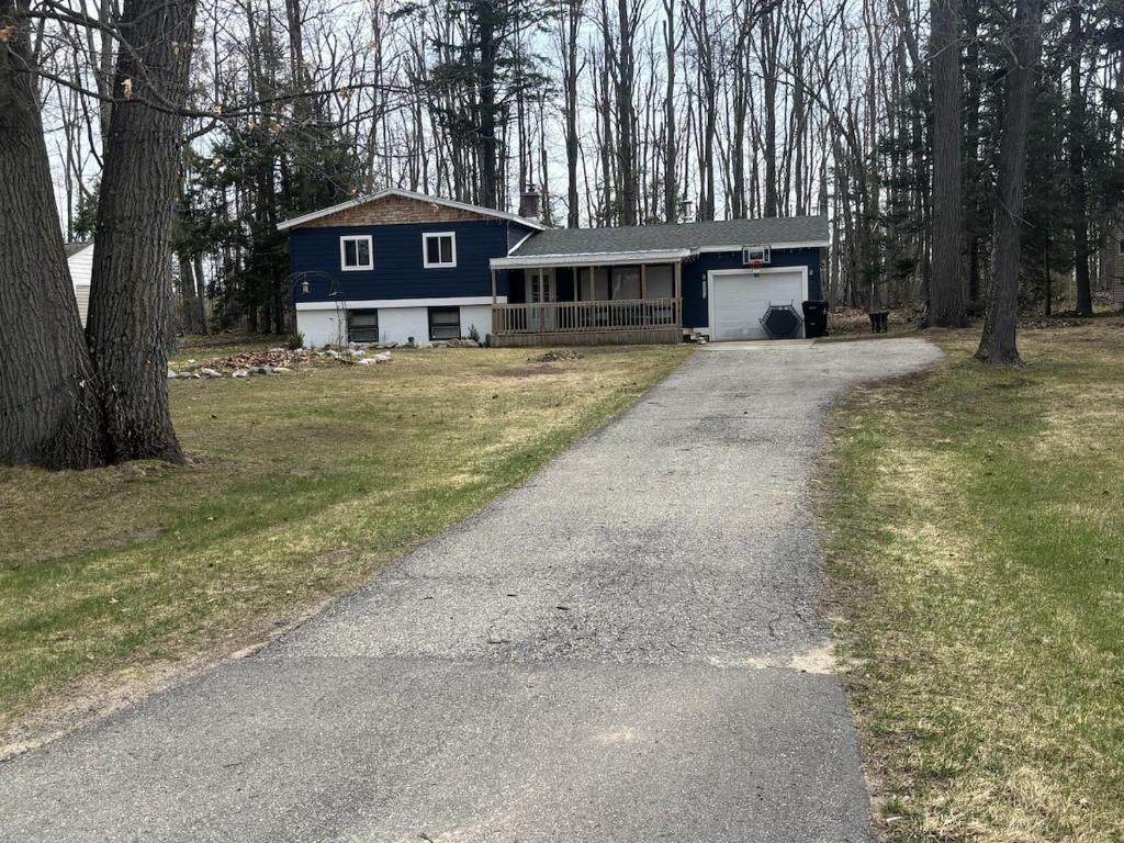 a driveway leading to a blue house with a garage at Trailside Lake Retreat in Gaylord