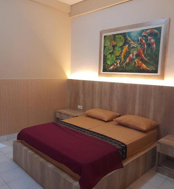 ein Schlafzimmer mit einem Bett und einem Gemälde an der Wand in der Unterkunft Hotel Pesaban in Tjakranegara